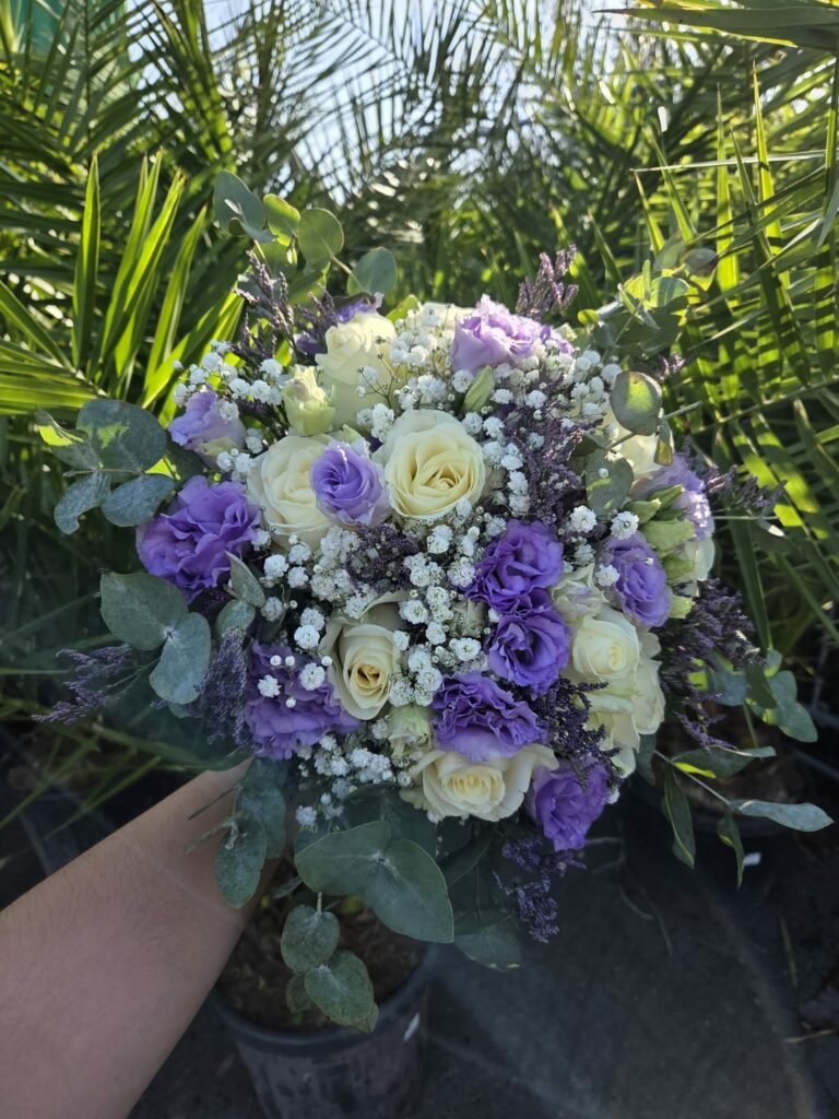 Bouquet de mariée parme et ivoire tenu à la main : lisianthus violets, roses ivoire, gypsophile, statice et eucalyptus