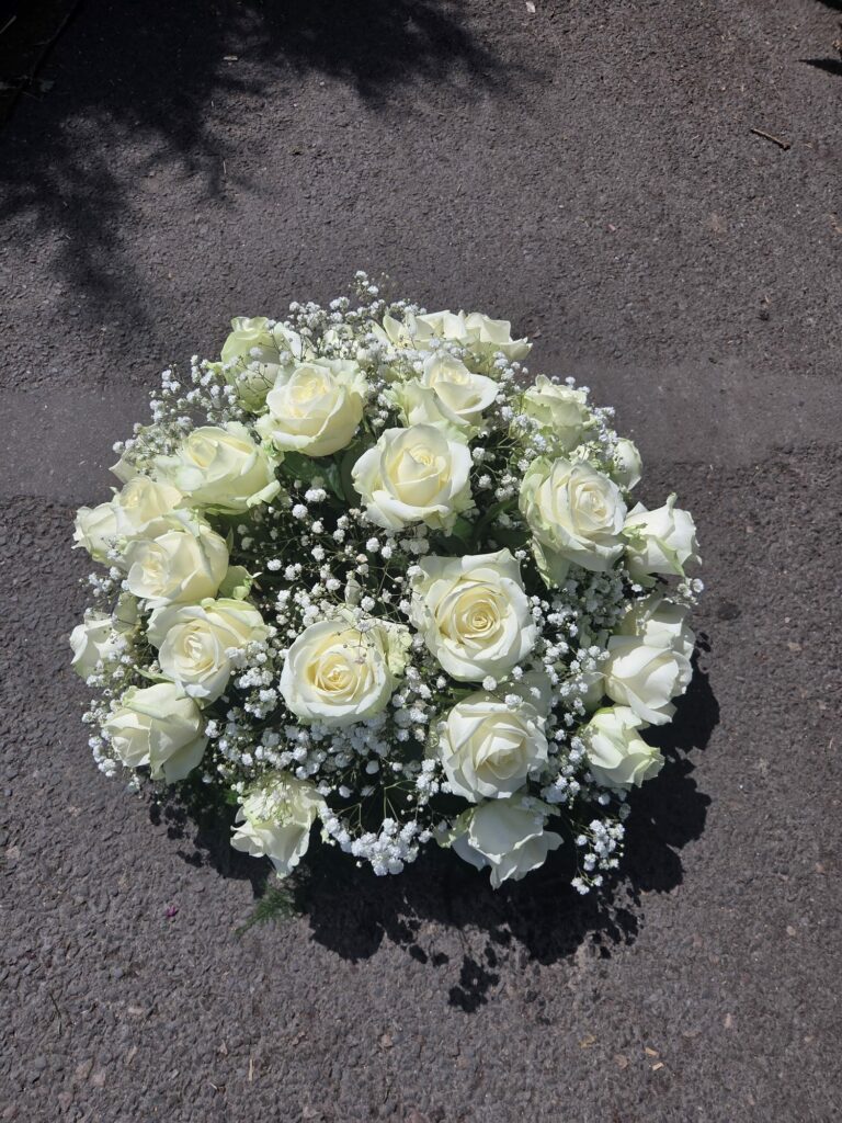 Bouquet rond composé de roses blanches et de gypsophile, vu de dessus