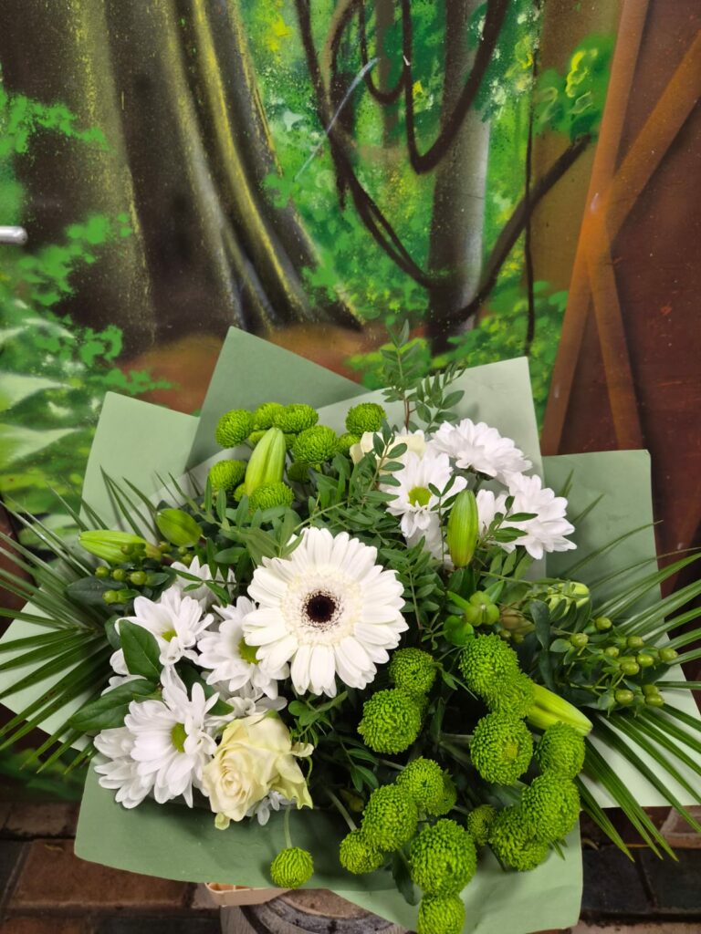 Bouquet blanc et vert : gerbera blanc, chrysanthèmes blancs, chrysanthèmes santini verts, rose blanche et boutons de lis, dans un papier vert d'eau