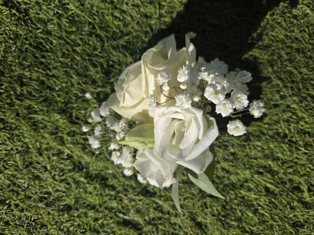 Boutonnière de mariage en gros plan : deux roses blanches, gypsophile et feuilles d'eucalyptus