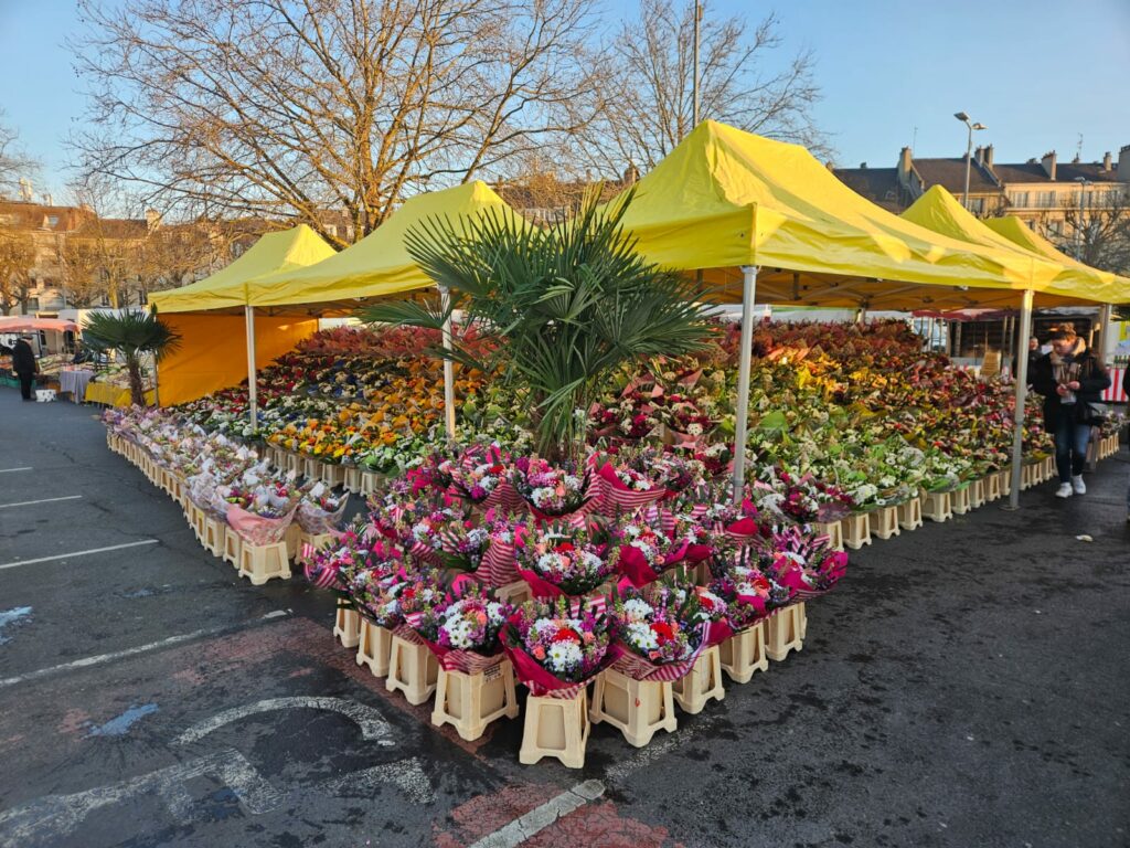 Le marché aux fleurs de la Jardinerie d'Ifs sous ses barnums jaunes : centaines de bouquets colorés présentés en gradins autour d'un palmier